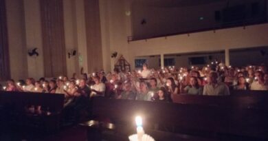 Foto escura, com velas acesas em um culto
